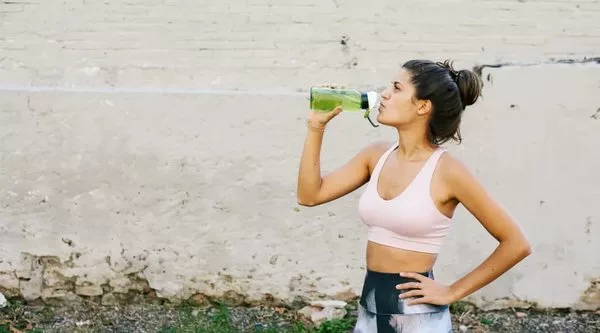 женщина пьет воду после тренировки