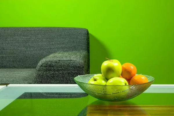 Зеленая комната, диван и фрукты в миске